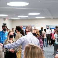 Multiple scholars giving poster presentations to guests, all wearing masks.